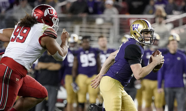 Washington quarterback Jake Browning, right, runs away from Utah defensive tackle Leki Fotu (99) du...