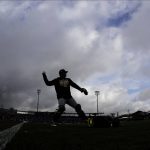 
              Oakland Athletics catcher Chris Herrmann is silhouetted against storm clouds as he warms up before a spring training baseball game against the Seattle Mariners, Friday, Feb. 22, 2019, in Peoria, Ariz. (AP Photo/Charlie Riedel)
            