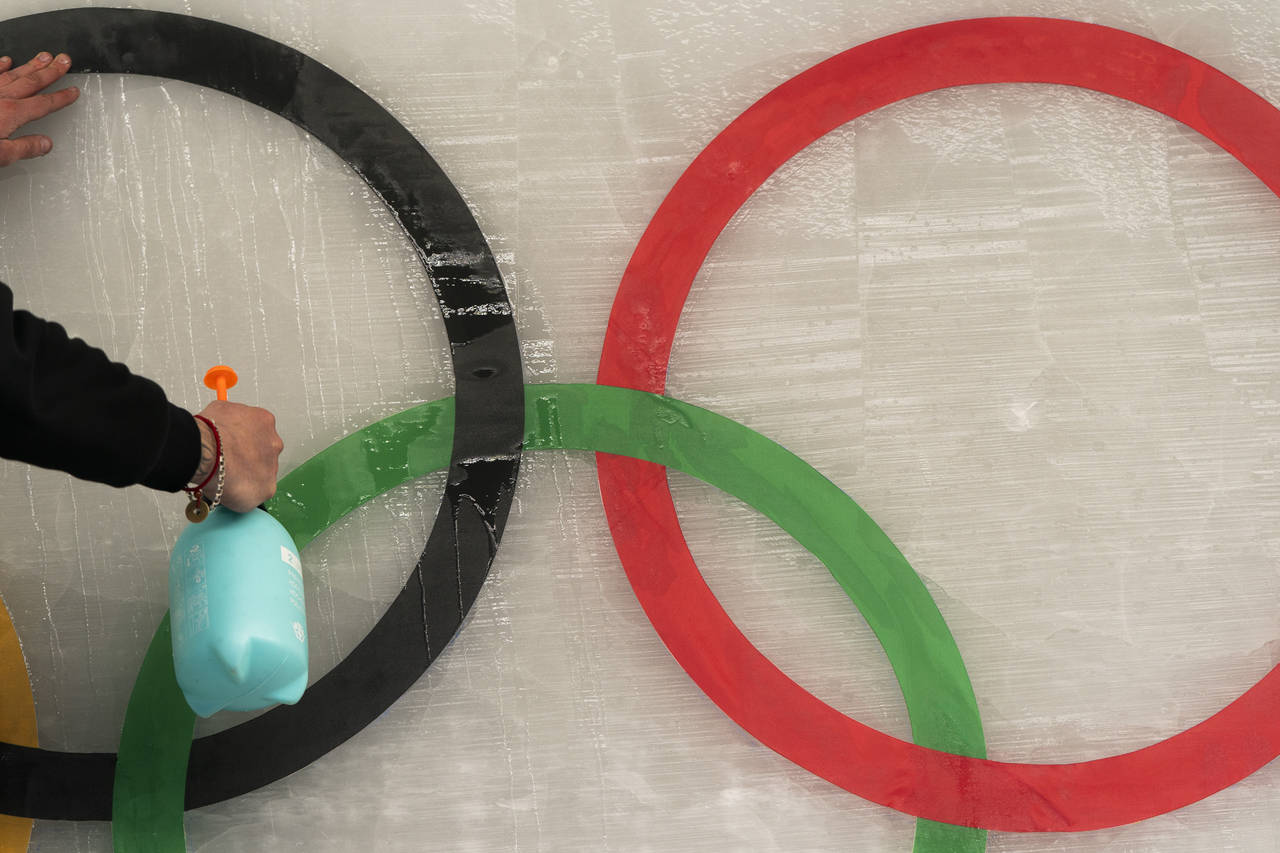 An ice maker sprays water over a cutout of the Olympic rings while installing a sub-glacial Beijing...