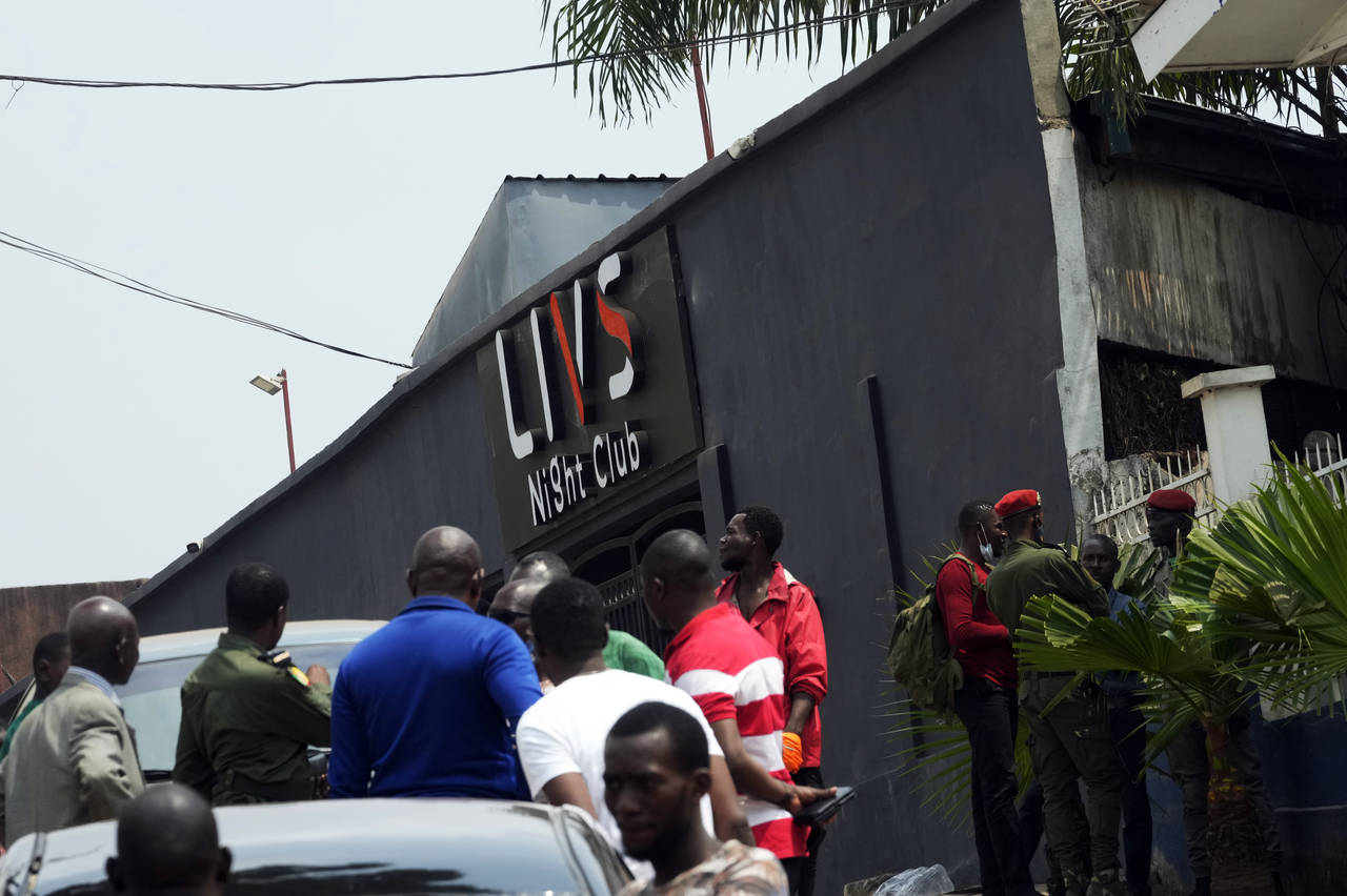 Police officers and officials stand outside the Livs Night Club in Yaounde, Cameroon, Sunday, Jan. ...