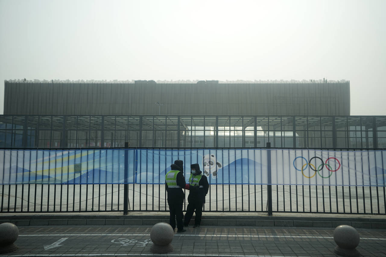 Security personnel stand on the sidewalk near Wukesong Sports Centre hockey venue ahead of the 2022...