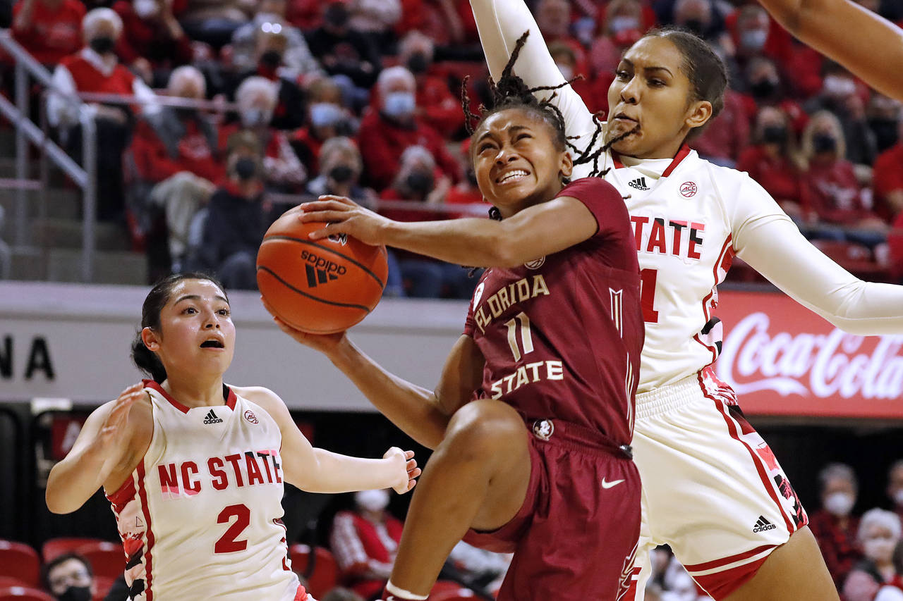 Florida State's O'Mariah Gordon (11) drives the ball between North Carolina State's Raina Perez (2)...