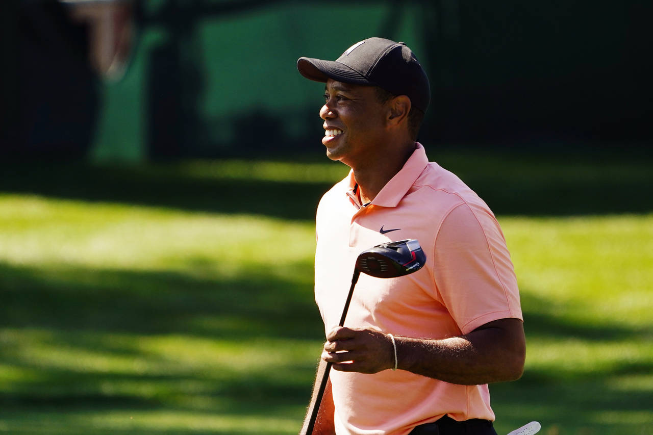 Tiger Woods smiles as he leaves the driving range during practice before the Masters golf tournamen...