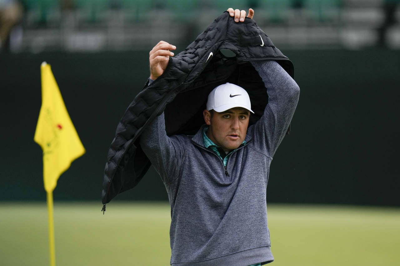 Scottie Scheffler puts on a vest on the fifth hole during the third round at the Masters golf tourn...