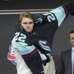 
              Shane Wright pulls on a Seattle Kraken jersey after being selected with the fourth pick in the NHL hockey draft in Montreal on Thursday, July 7, 2022. (Ryan Remiorz/The Canadian Press via AP)
            
