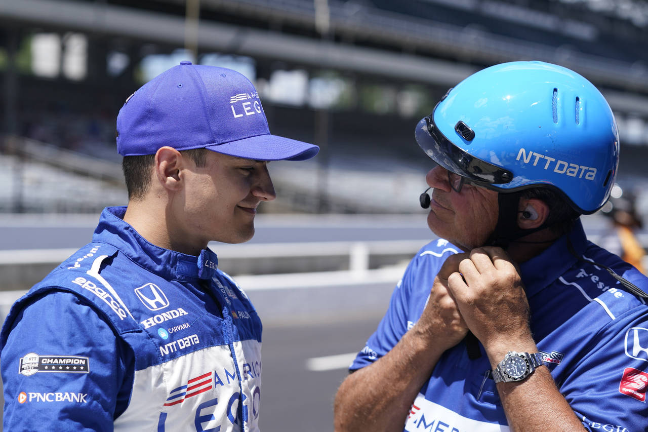 Alex Palou, of Spain, left, talks with a crew member during qualifications for a IndyCar auto race ...