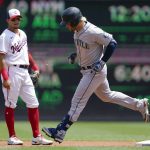 
              Seattle Mariners' Eugenio Suarez rounds the bases past Washington Nationals second baseman Cesar Hernandez after hitting a three-run home run in the first inning of the first game of a baseball doubleheader, Wednesday, July 13, 2022, in Washington. (AP Photo/Patrick Semansky)
            