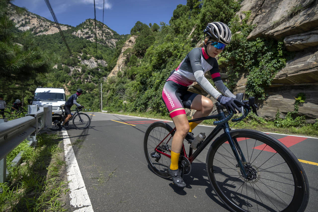 Members of the Qiyi bicycle club climb a hill on a rural road during a group ride through the Baihe...