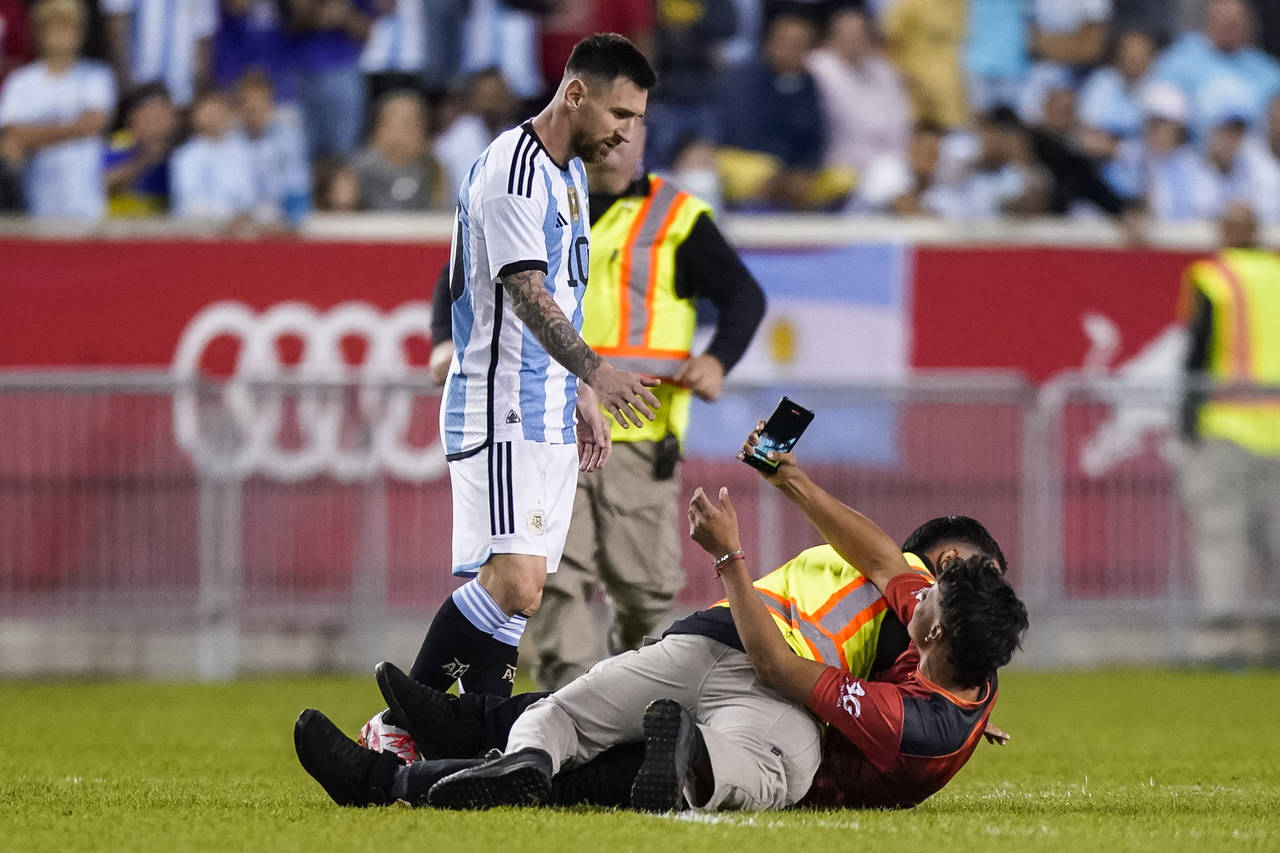 A fan is tackled as he tries to take a picture of Argentina's player Lionel Messi during the second...