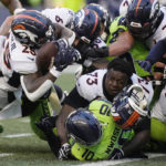 
              Denver Broncos running back Melvin Gordon III, upper left, fumbles the ball as Broncos offensive tackle Cameron Fleming (73) loses his helmet during the second half of an NFL football game against the Seattle Seahawks, Monday, Sept. 12, 2022, in Seattle. (AP Photo/Stephen Brashear)
            