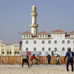 Laborers play sandlot cricket near World Cup soccer stadiums
