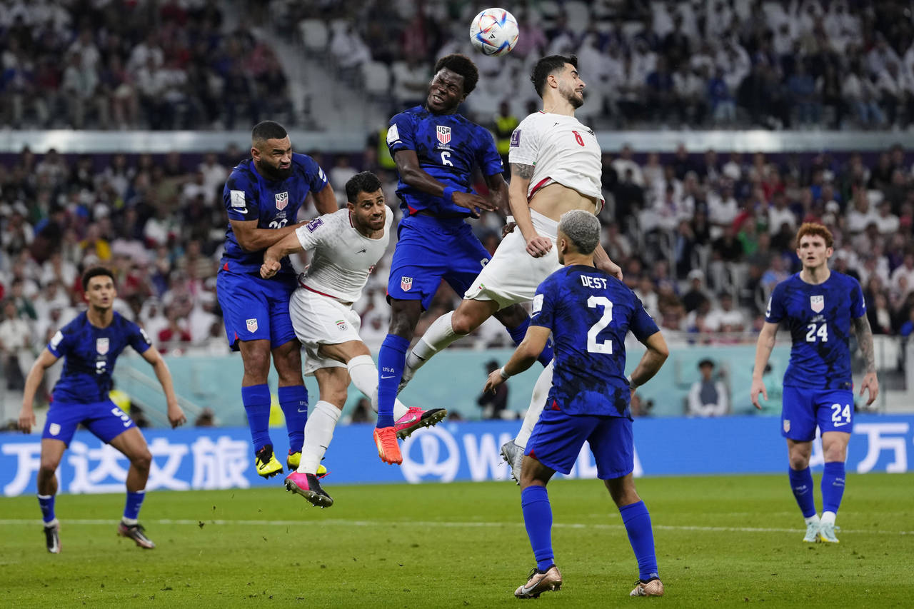 Players fight for a header during the World Cup group B soccer match between Iran and the United St...
