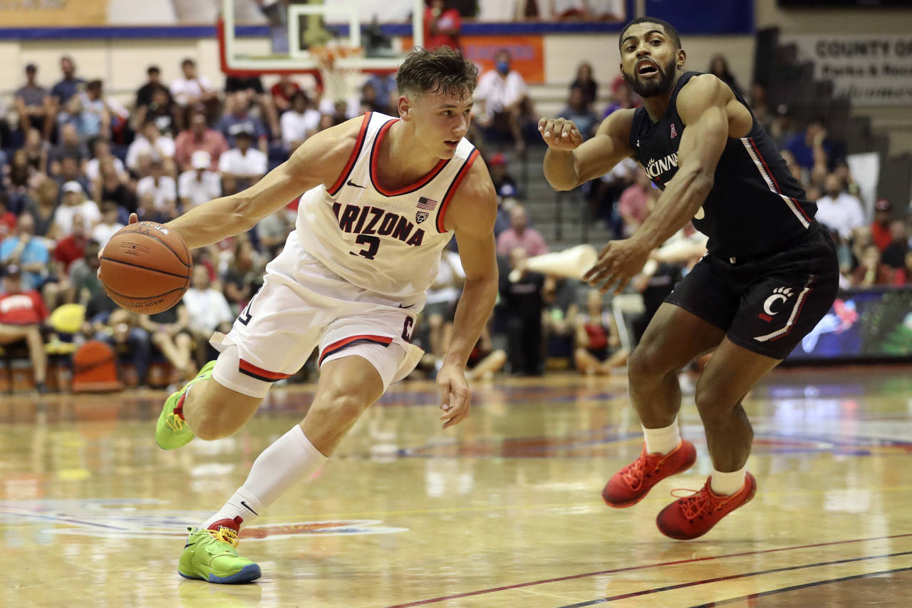 Cincinnati guard David DeJulius (5) chases Arizona guard Pelle Larsson (3) during the second half o...