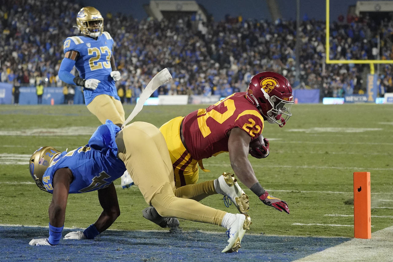 Southern California running back Darwin Barlow, right, dives in for a touchdown as UCLA defensive b...