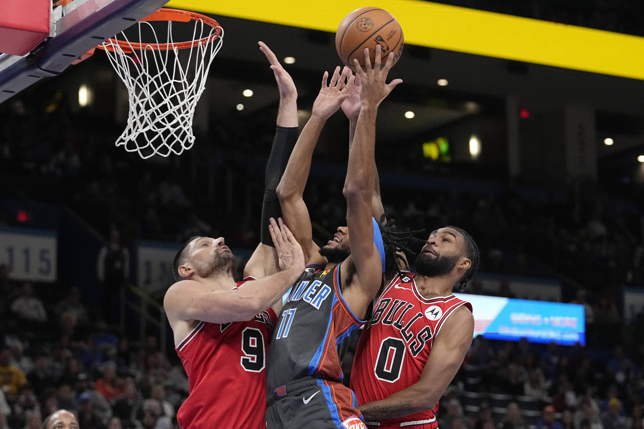 Oklahoma City Thunder guard Isaiah Joe (11) shoots between Chicago Bulls center Nikola Vucevic (9) ...
