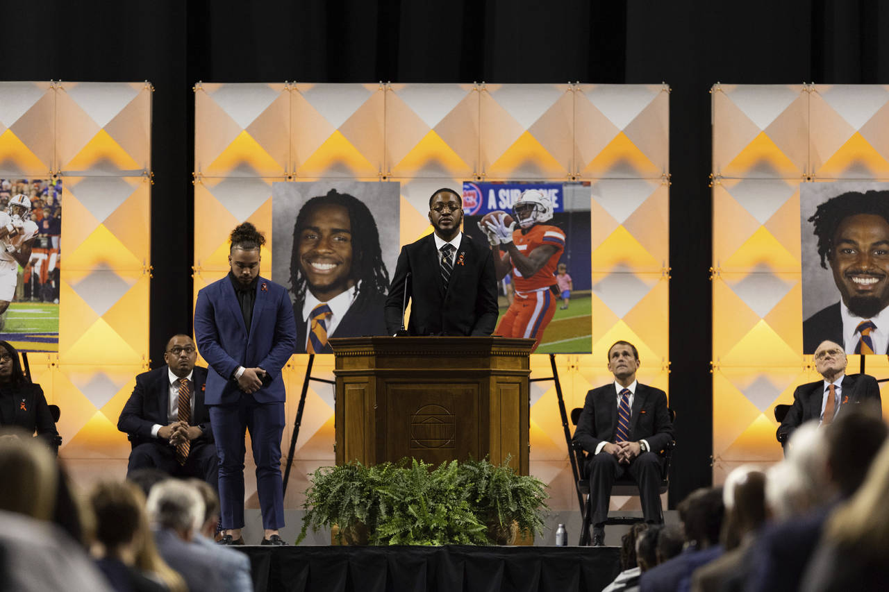 A football player speaks to a crowd during a memorial service in Charlottesville, Va., Saturday, No...