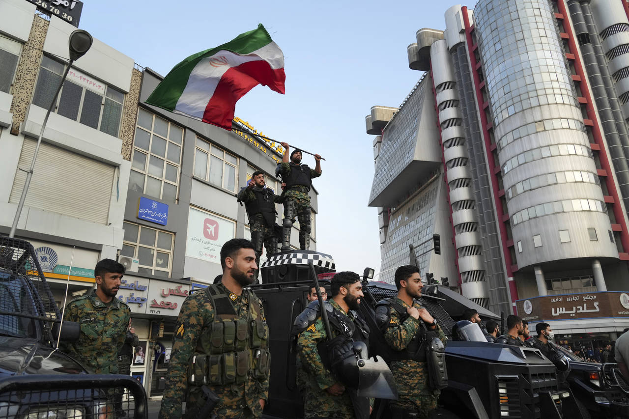 An anti-riot police officer waves a representation of the Iranian flag during a street celebration ...