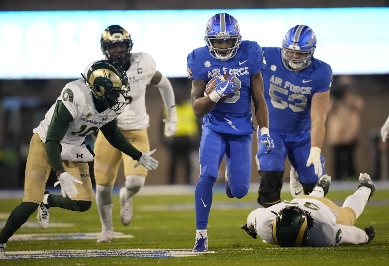 Air Force wide receiver DeAndre Hughes, center, breaks for a long gain as Colorado State defensive ...