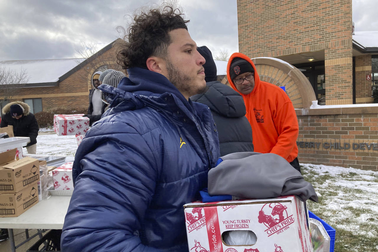 Michigan running back Blake Corum carries a tray containing a turkey, vegetables and other items du...