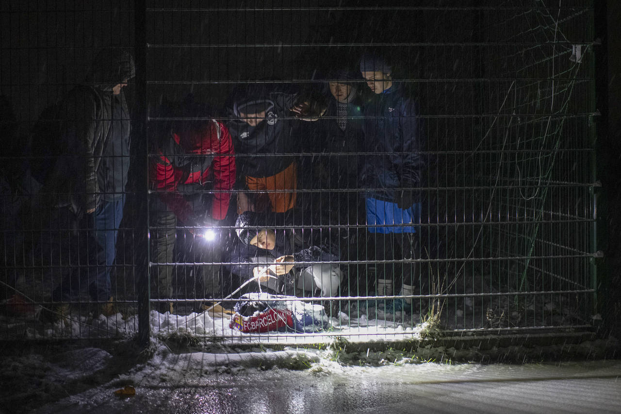 Men connect a homemade light with a battery to illuminate the pitch ahead of a soccer game during a...