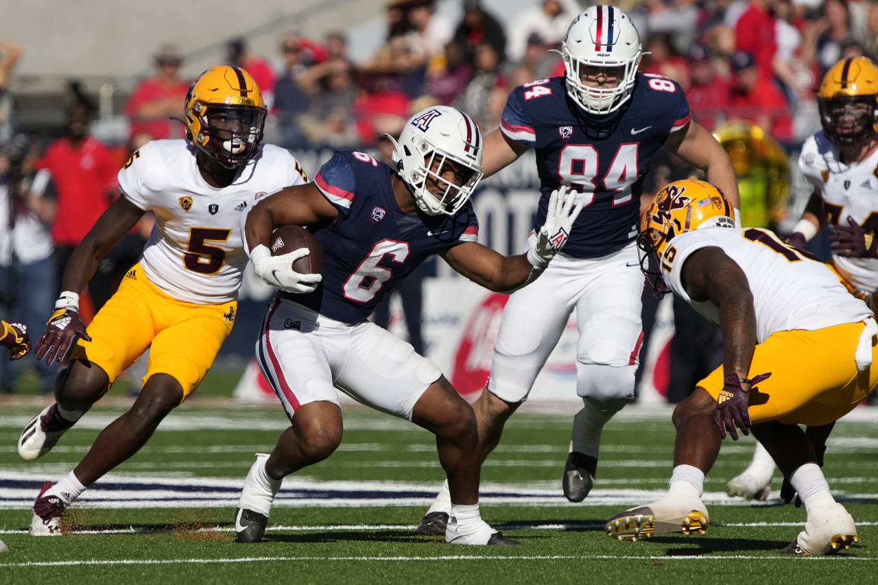 Arizona running back Michael Wiley (6) runs the ball between Arizona State defensive backs Chris Ed...