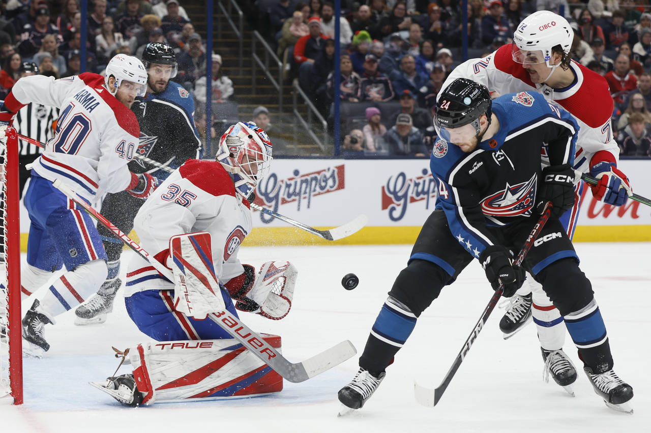 Montreal Canadiens' Sam Montembeault, left, makes a save as teammate Arber Xhekaj, right, and Colum...