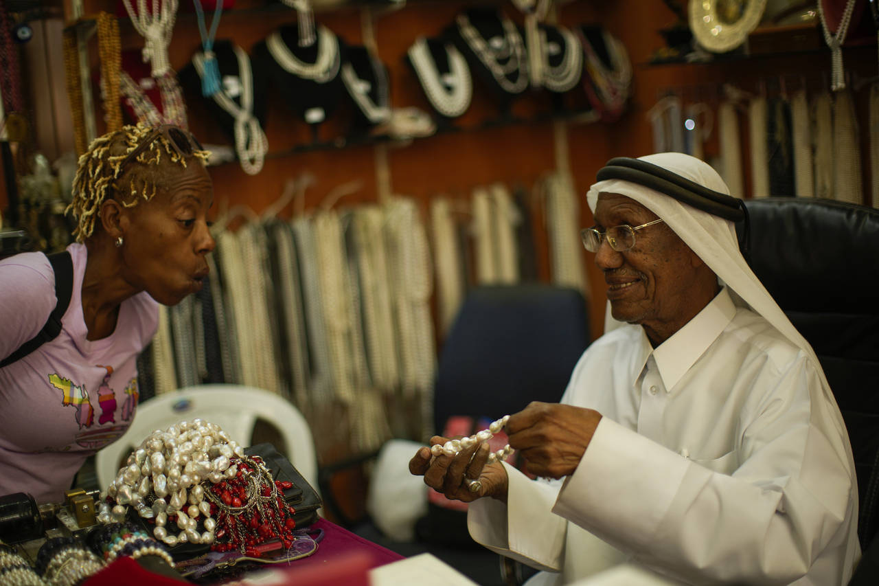 A former pearl diver Saad Ismail talks to a client in his pearl shop in Souq Waqif market in Doha, ...