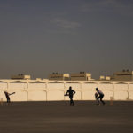 Laborers play sandlot cricket near World Cup soccer stadiums