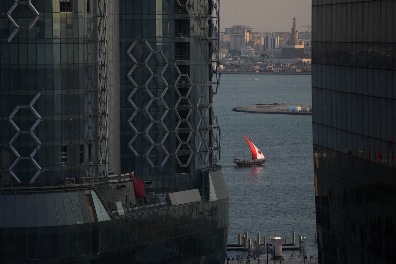A boat with a Canadian flag sail moves through Doha Harbor, in Doha, Tuesday, Nov. 22, 2022. (AP Ph...