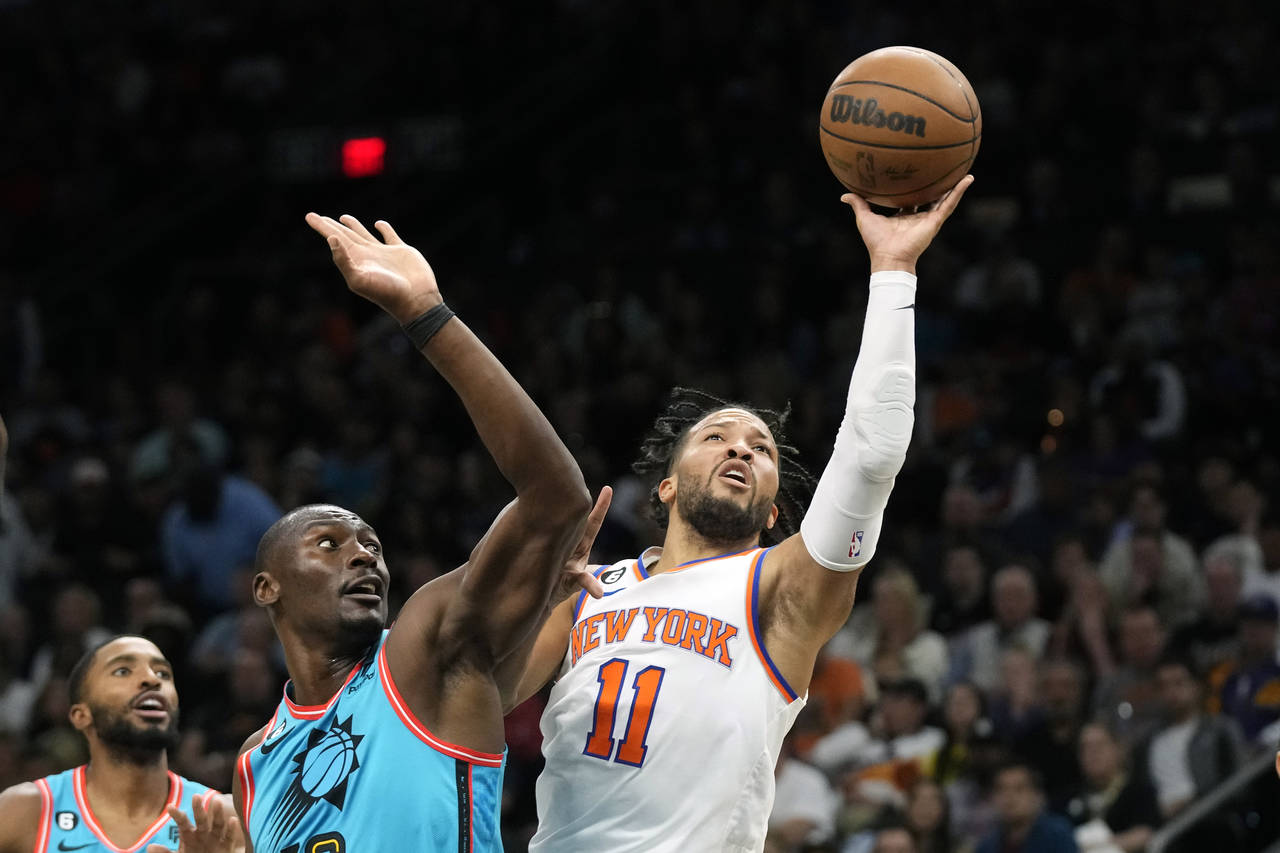 New York Knicks guard Jalen Brunson (11) drives past Phoenix Suns center Bismack Biyombo, center, a...
