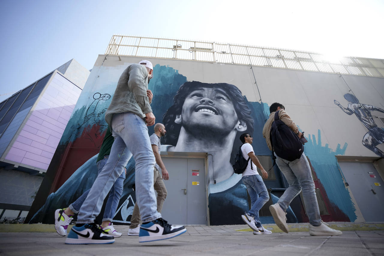 People walk past a mural of former Argentine player Diego Maradona, who led his country to the 1986...