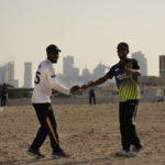 Laborers play sandlot cricket near World Cup soccer stadiums