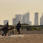 Laborers play sandlot cricket near World Cup soccer stadiums