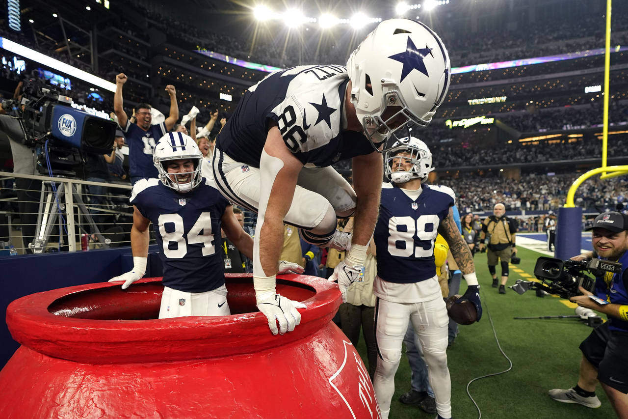 Dallas Cowboys' Dalton Schultz (86) jumps out of a Salvation Army kettle while celebrating Peyton H...