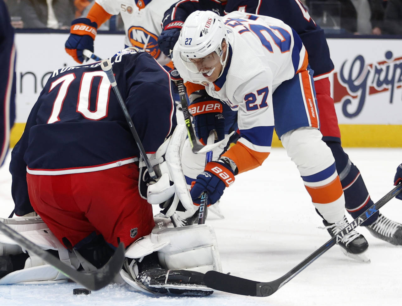 Columbus Blue Jackets goalie Joonas Korpisalo, left, stops a shot in front of New York Islanders fo...