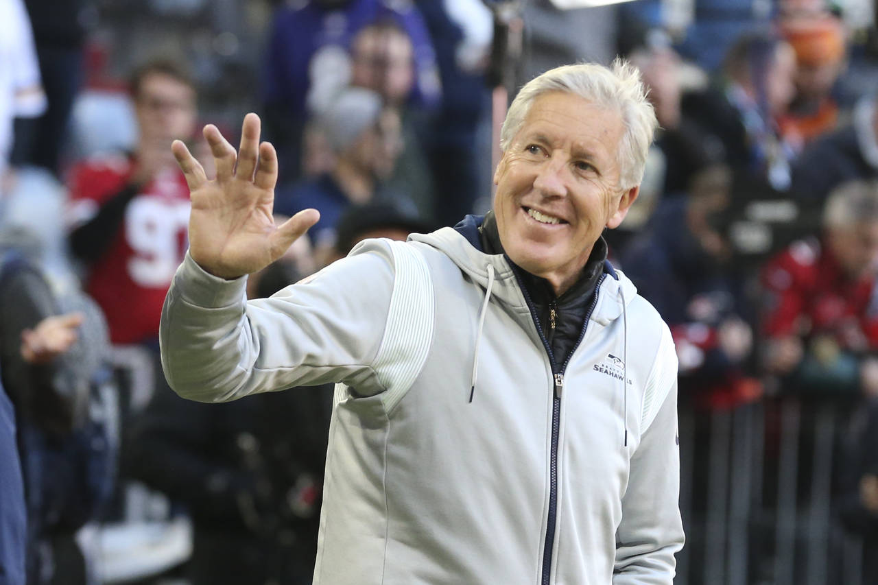 Seattle Seahawks head coach Pete Carroll waves to fans as he walks onto the field before an NFL foo...