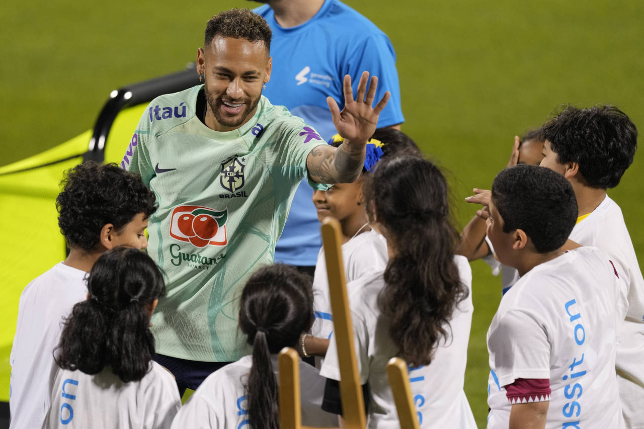 Brazil's Neymar greets children from a FIFA social project after a training session at the Grand Ha...