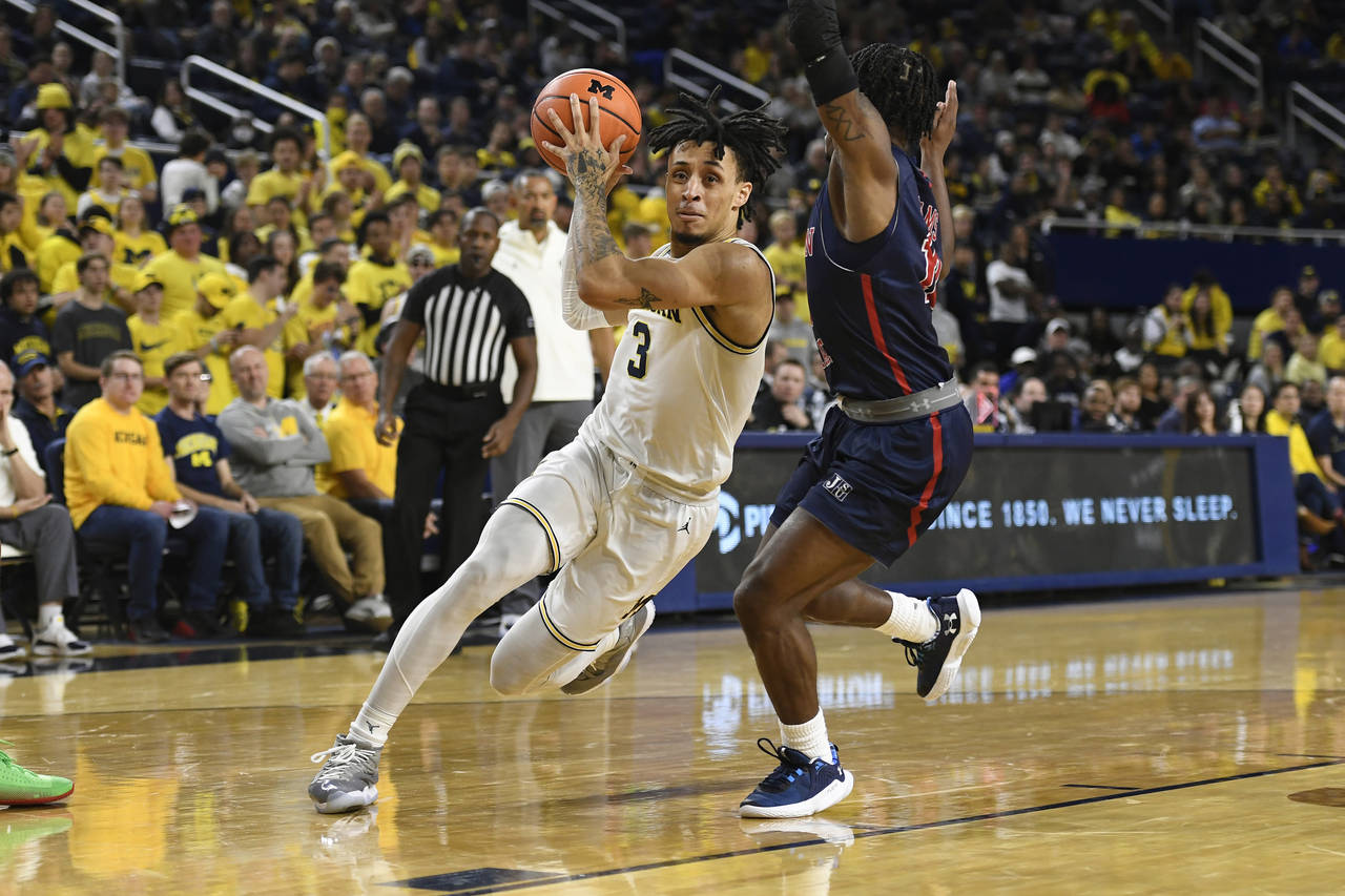 Michigan guard Jaelin Llewellyn, left, drives to the basket as he is guarded by Jackson State guard...