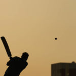 Laborers play sandlot cricket near World Cup soccer stadiums