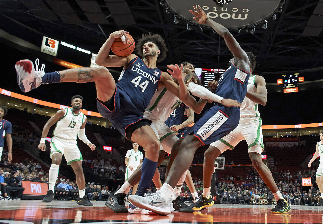 Connecticut forward Alex Karaban (44) collects a rebound ahead of Oregon guard Rivaldo Soares, cent...