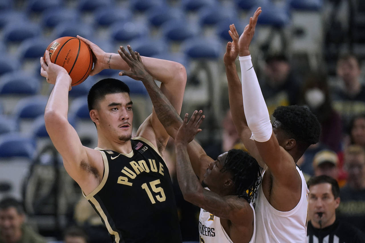 West Virginia's Kedrian Johnson, center, and Mohamed Wague, right, defend against Purdue center Zac...