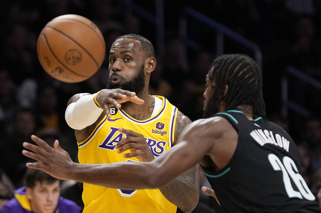 Los Angeles Lakers forward LeBron James, left, passes the ball as Portland Trail Blazers forward Ju...
