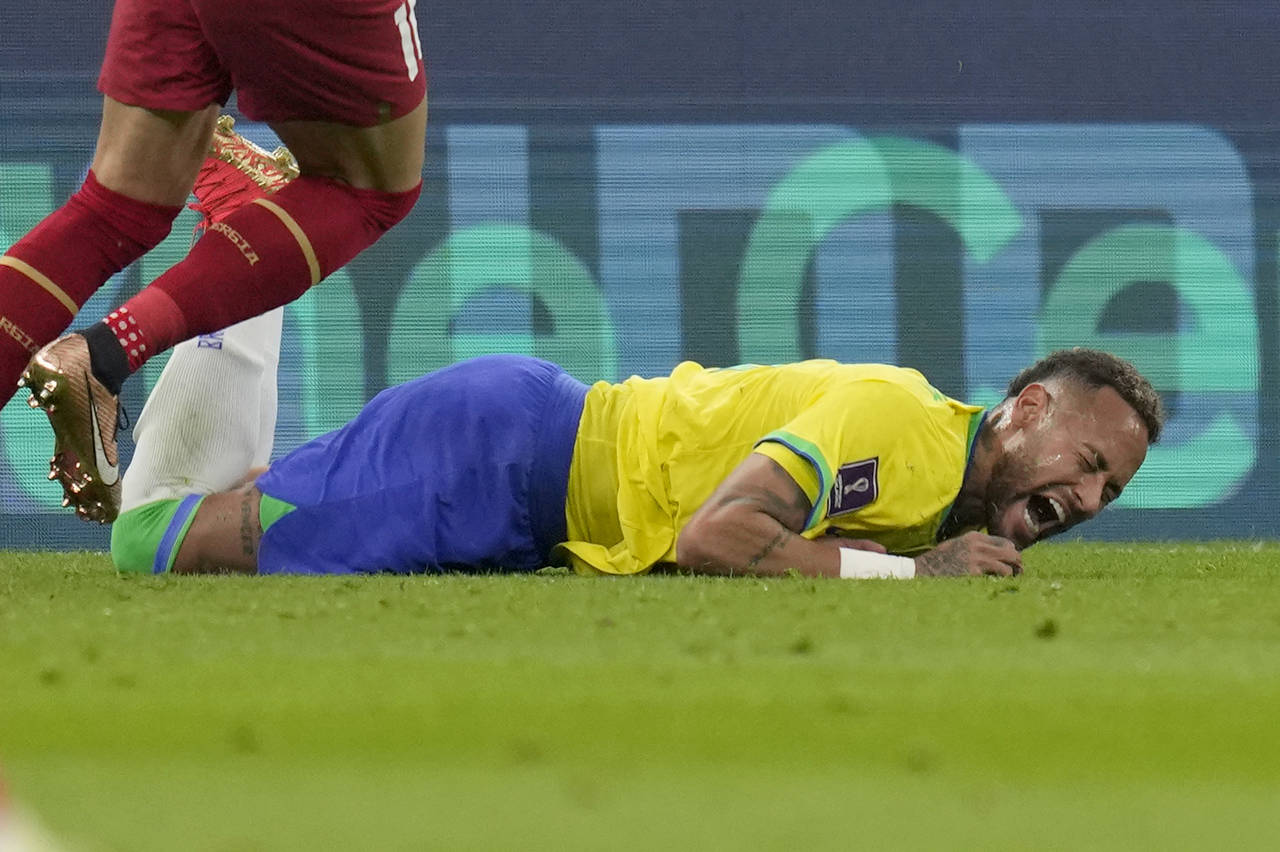 Brazil's Neymar grimaces as he falls to the ground during the World Cup group G soccer match betwee...
