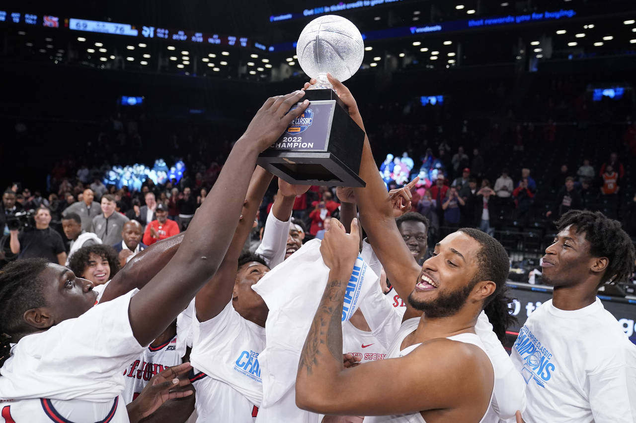 St. John's Joel Soriano, center right, raises the championship trophy as he celebrates with his tea...
