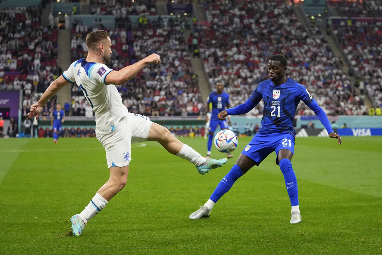 England's Luke Shaw, left, fights for the ball against Tim Weah of the United States during the Wor...