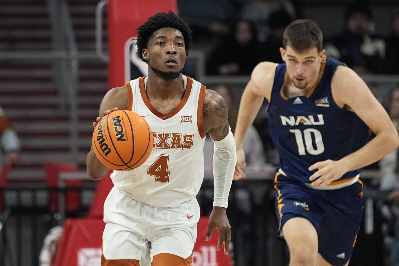 Texas guard Tyrese Hunter (4) moves the ball past Northern Arizona forward Jack Wistrcill (10) duri...