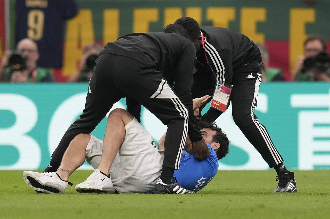 A pitch invader runs is caught while running across the field with a rainbow flag during the World ...