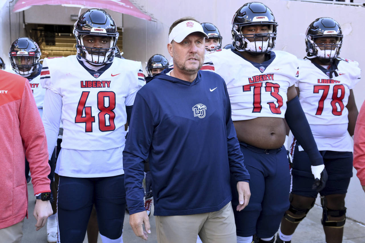 Liberty head coach Hugh Freeze, center, gets ready to take the field with his team to play Arkansas...