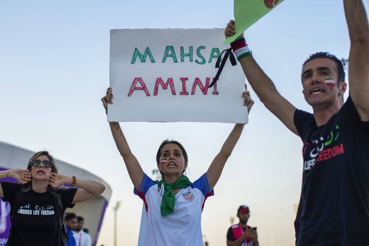 A woman holds up a sign reading Mahsa Amini, a woman who died while in police custody in Iran at th...