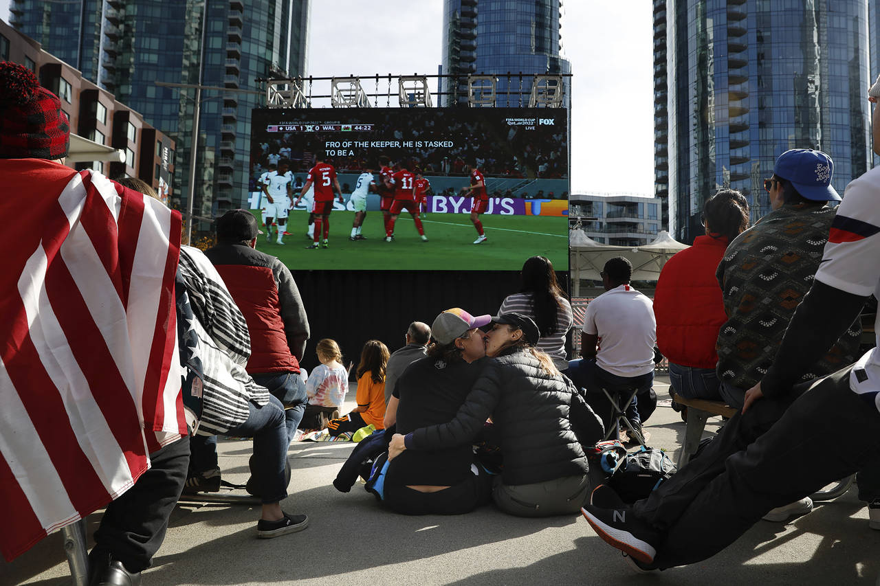 A couple kiss under the big screen as they watch the U.S. vs Wales World Cup Soccer game at The Cro...